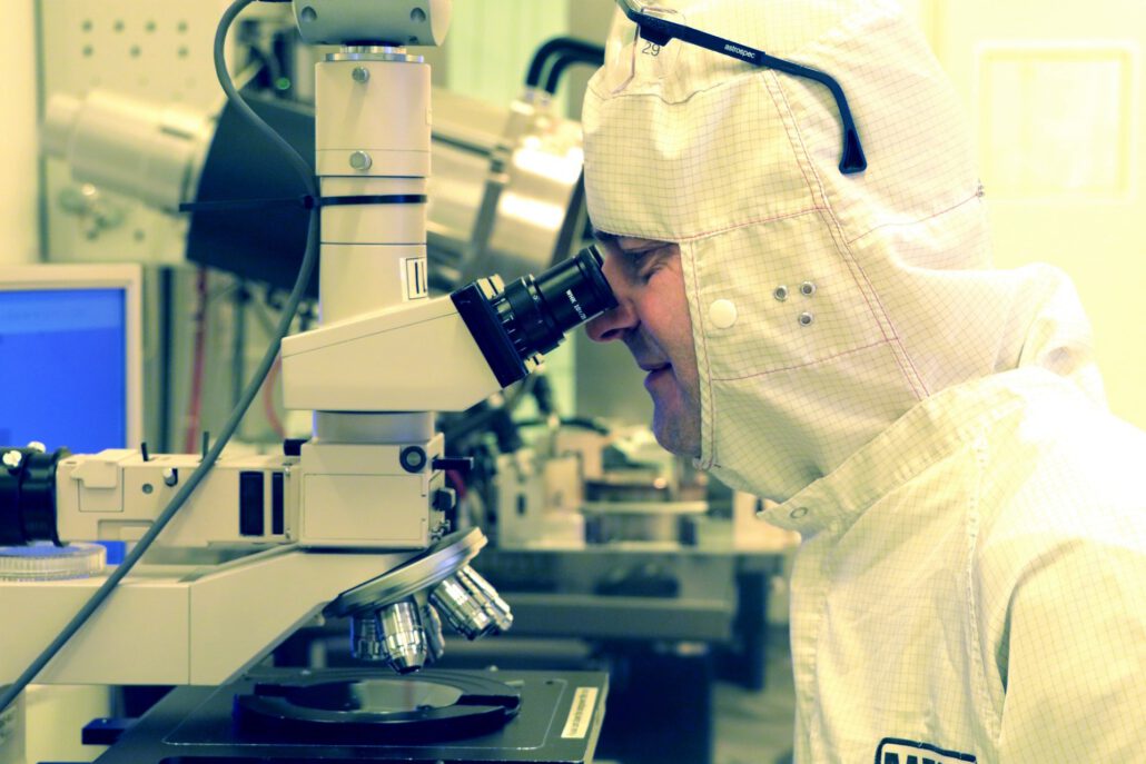 examining a custom MEMS chip wafer An engineer using a microscope to examine a MEMS chip wafer as part of MEMS development